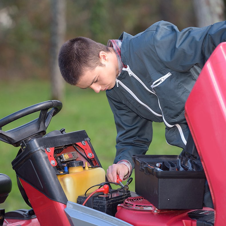 Young man working garden tractor engine