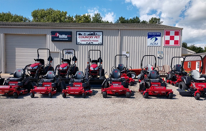 Group of red z-turn mowers and utility tractors parked in front of garage