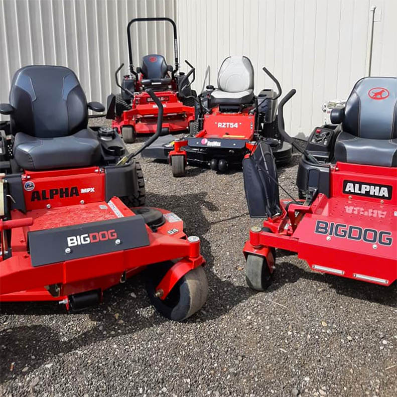 red alpha big dog z-turn lawn mowers parked by barn